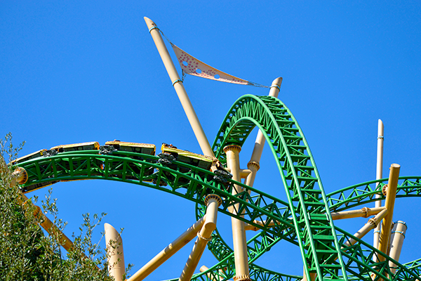 Green roller coaster against sky